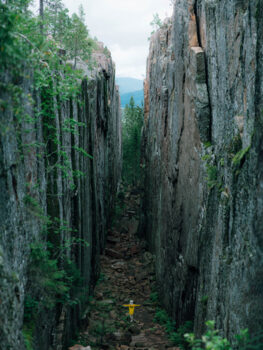 A woman walks between two mountain walls in what is called 'Slåttdalsskrevan' in the High Coast.