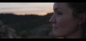A close-up of a woman looking at the view while standing outside during the evening.